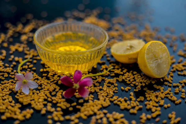 natural hair conditioner for dandruff consisting of fenugreek seeds powder well mixed with lemon juice in glass bowl with raw lemons and fenugreek seeds on wooden surface