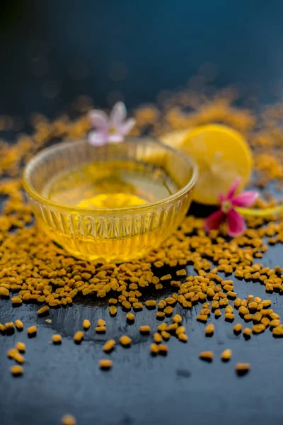 natural hair conditioner for dandruff consisting of fenugreek seeds powder well mixed with lemon juice in glass bowl with raw lemons and fenugreek seeds on wooden surface