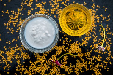 A famous natural method for dandruff on wooden surface in a glass bowl consisting of fenugreek seeds powder well-mixed with curd in a glass bowl.Along with raw curd and fenugreek seeds on the surface. clipart
