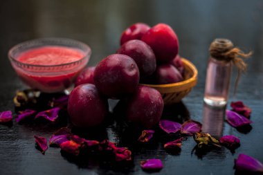 Başka bir cam kase onun hamur ile birlikte şeffaf bir cam şişe içinde çıkarılan uçucu yağ ile birlikte kahverengi renkli bir sepet içinde Ham organik kırmızı olgun erik.