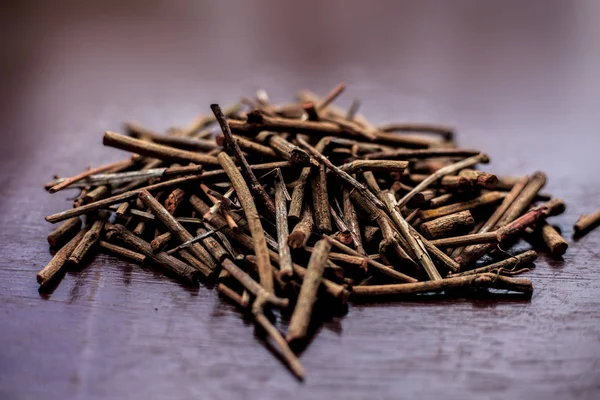 Eski Ayurveda'dan elde edilen çeşitli sağlık yararları ile manjistha/manzistha/Rubia cordifolia/madder vb. olarak da bilinen kahverengi renkli ahşap yüzeyde Hint madderwort veya madder kökü Demeti.