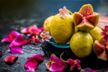 Ham organik guava veya amrut veya amarood Hintçe dilinde siyah parlak yüzeyüzerinde bazı gül yaprakları ile mavi renkli plaka.