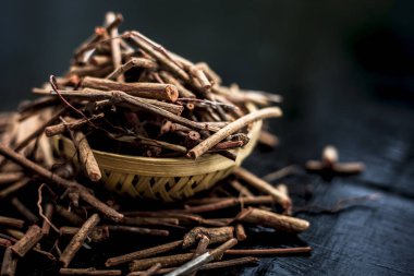 Manjistha/manzistha/Rubia cordifolia/madder vb. olarak da bilinen siyah ahşap yüzeyde kahverengi renkli bir sepetiçinde Hint madderwort veya madder kök Demet.