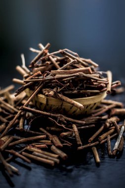 Manjistha/manzistha/Rubia cordifolia/madder vb. olarak da bilinen siyah ahşap yüzeyde kahverengi renkli bir sepetiçinde Hint madderwort veya madder kök Demet.