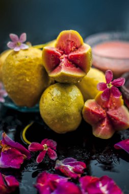 Ham organik guava veya amrut veya amarood Hintçe dilinde siyah parlak yüzeyüzerinde bazı gül yaprakları ile mavi renkli plaka.