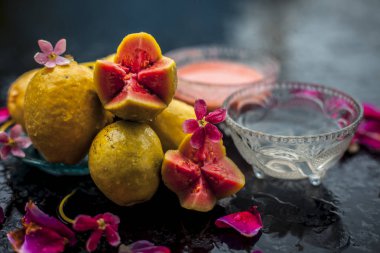 Guava hamuru ve su kuyusu bazı ham kesim guava ile birlikte ahşap yüzeyinde bir cam kase karışık, bazı gül yaprakları ile, aynı zamanda doğal bir parlaklık için kullanılan bir yüz maskesi tamamlayarak.