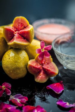 Guava hamuru ve su kuyusu bazı ham kesim guava ile birlikte ahşap yüzeyinde bir cam kase karışık, bazı gül yaprakları ile, aynı zamanda doğal bir parlaklık için kullanılan bir yüz maskesi tamamlayarak.