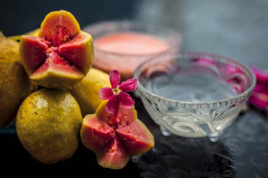 Guava hamuru ve su kuyusu bazı ham kesim guava ile birlikte ahşap yüzeyinde bir cam kase karışık, bazı gül yaprakları ile, aynı zamanda doğal bir parlaklık için kullanılan bir yüz maskesi tamamlayarak.