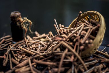 Manjistha/manzistha/Rubia cordifolia/madder vb. olarak da bilinen siyah ahşap yüzeyde kahverengi renkli bir sepetiçinde Hint madderwort veya madder kök Demet.