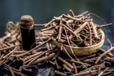 Manjistha/manzistha/Rubia cordifolia/madder vb. olarak da bilinen siyah ahşap yüzeyde kahverengi renkli bir sepetiçinde Hint madderwort veya madder kök Demet.