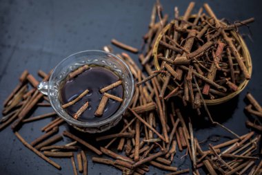 Bir bardak çayı ile manjistha / manzistha / Rubia cordifolia / madder vb olarak da bilinen siyah ahşap yüzeyüzerinde kahverengi renkli sepet hint madderwort veya madder kök Demet.