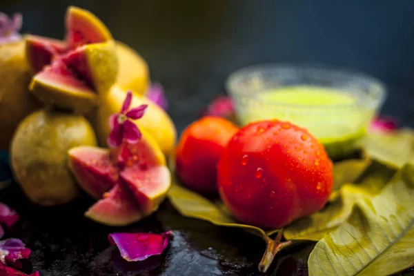 Best cheap face mask for tanned skin on wooden surface un a glass bowl consisting of guava leaves paste well mixed with some tomato pulp. Shot with entire ingredients with fantastic colors.