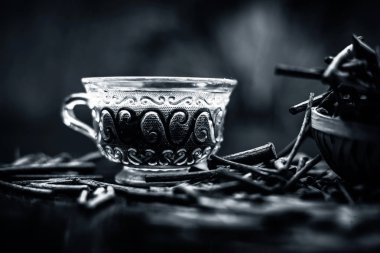 Bir bardak çayı ile manjistha / manzistha / Rubia cordifolia / madder vb olarak da bilinen siyah ahşap yüzeyüzerinde kahverengi renkli sepet hint madderwort veya madder kök Demet.