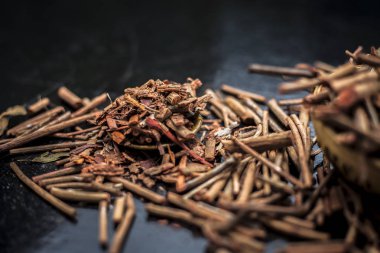 Küçük kahverengi bir plaka içinde toz ile de manjistha / manzistha / Rubia cordifolia / madder vb olarak bilinen siyah ahşap yüzeyüzerinde kahverengi renkli sepet hint madderwort veya madder kök Demet.