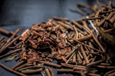 Küçük kahverengi bir plaka içinde toz ile de manjistha / manzistha / Rubia cordifolia / madder vb olarak bilinen siyah ahşap yüzeyüzerinde kahverengi renkli sepet hint madderwort veya madder kök Demet.