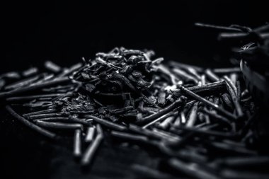 Küçük kahverengi bir plaka içinde toz ile de manjistha / manzistha / Rubia cordifolia / madder vb olarak bilinen siyah ahşap yüzeyüzerinde kahverengi renkli sepet hint madderwort veya madder kök Demet.