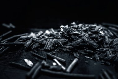 Küçük kahverengi bir plaka içinde toz ile de manjistha / manzistha / Rubia cordifolia / madder vb olarak bilinen siyah ahşap yüzeyüzerinde kahverengi renkli sepet hint madderwort veya madder kök Demet.