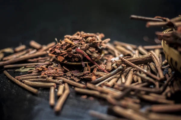 Küçük kahverengi bir plaka içinde toz ile de manjistha / manzistha / Rubia cordifolia / madder vb olarak bilinen siyah ahşap yüzeyüzerinde kahverengi renkli sepet hint madderwort veya madder kök Demet.