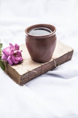 Kil kupa tek pembe renkli gül ve kahve ile beyaz kumaş Vintage eski kitap 