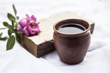 Kil kupa tek pembe renkli gül ve kahve ile beyaz kumaş Vintage eski kitap 