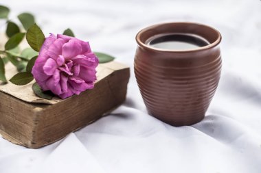 Kil kupa tek pembe renkli gül ve kahve ile beyaz kumaş Vintage eski kitap 