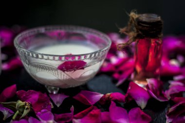 Taze süt, cam kasede gül suyuyla karıştırılmış ahşap yüzeyde yapraklarla.