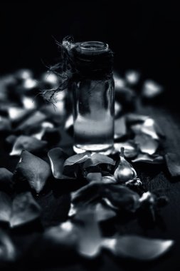 Gül yapraklarıyla şeffaf cam şişede gül yağı.