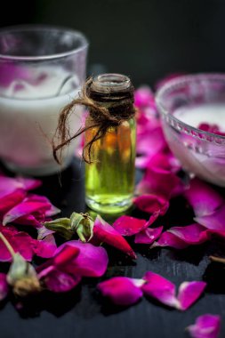 Gül sütü, süt kremi ve zeytin yağını içeren yüz bakımı ahşap yüzeyde cam bir kâse ve bazı gül yapraklarıyla birlikte..