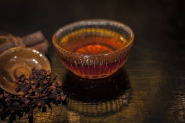 Küçük bardakta çay ve masada karanfil.