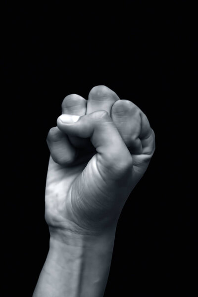 male hand in fist on black background