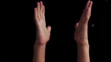 Bir çift geveze insan eli, siyah arka planda izole bir şekilde yukarı çıkıyor..