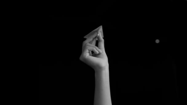 人間の手は紙飛行機を考え出し 黒い色の背景に孤立して遊んでいます — ストック動画
