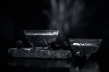 Nutmeg baharat maskesi siyah yüzey üzerinde hindistan cevizi veya cam bir kasede bulunan biraz lor tozu ile karıştırılmış. Çiğ baharat ve kaymak ile vurulmuş. Yatay üstten çekim.