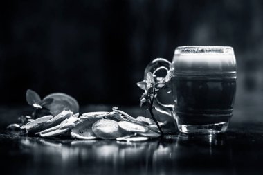 Ahşap yüzeyde taze havuç suyuyla dolu cam bardak yanında havuç dilimleri ve masada mentha yaprakları. Arka planda bulanıklık olan yatay çekim..