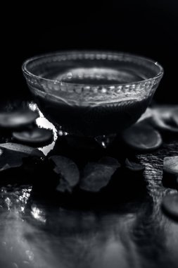 Siyah ahşap bir yüzey üzerinde havuç maskesi. İçinde taze kesilmiş havuç ezmesi, limon suyu ve bal var. Sivilce tedavisi için cam bir kaseye karıştırılmış..  