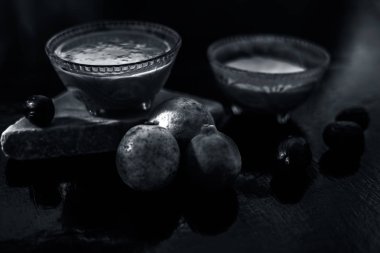 Ahşap yüzeyde, arkaplanı bulanık olan baharat maskesi biraz hindistan cevizi tozu, yoğurt ve cam kaseye karıştırılmış limon suyu içeriyor. Çiğ hindistan cevizi, yüz maskesi ve limonlu görüntü.