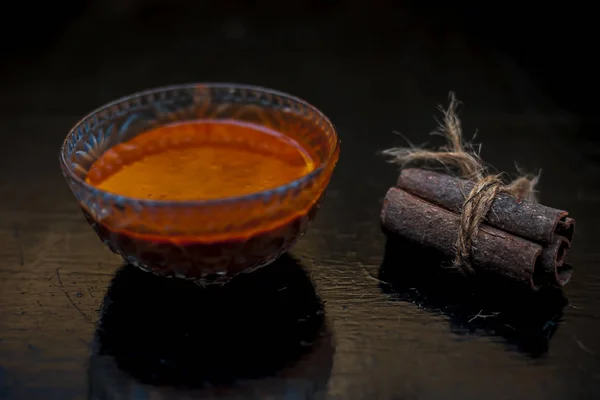 肉桂和蜂蜜毛膜在一个玻璃碗在木制表面与黄金灯隔离 还有表面上的生肉桂棒和蜂蜜 — 图库照片