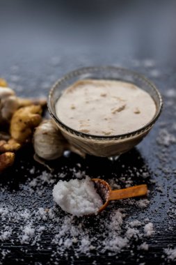 Siyah bir yüzey üzerinde cam bir kasede taze sarımsak ve zencefil ezmesi ve yüzeyine tuz serpiştirilmiş biraz sarımsak. Lasan adrak ka macunu ahşap yüzeyde cam bir kaseye yapıştı..