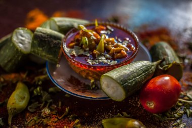 Gujarati 'nin ünlü Galka Nu Shaak' ını cam bir tabakta yakın plan çek. Cam bir tabakta bir bardak sünger kabağı ve taze domates ve sünger kabağıyla birlikte kahverengi bir tabağın üzerindeki tüm baharatlar..
