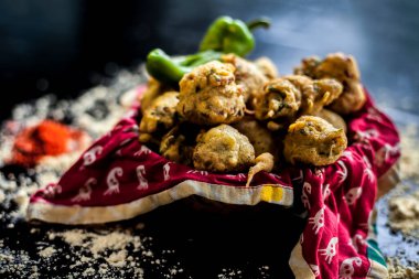 Yüzeyine biraz baharat ve nohut unu serpiştirilmiş taze yağda kızartılmış metipakora 'yı kapta yakın çekim yapın. Methi pakora, siyah yüzeyde servis tabağında..