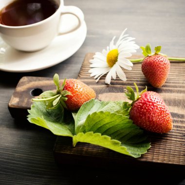 Bir fincan çay. Ahşap arka plan. Olgun, lezzetli ve çilekli. Koyu sıcak çay.