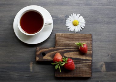 Bir fincan çay. Ahşap arka plan. Olgun, lezzetli ve çilekli. Koyu sıcak çay.