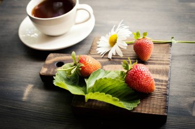 Bir fincan çay. Ahşap arka plan. Olgun, lezzetli ve çilekli. Koyu sıcak çay.