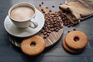 Ahşap arka planda bir fincan kahve. Sütlü kahve. Kahve çekirdeği.