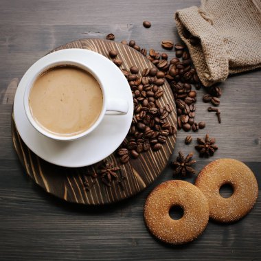 Ahşap arka planda bir fincan kahve. Sütlü kahve. Kahve çekirdeği.