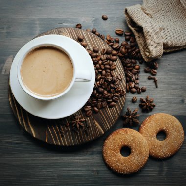 Ahşap arka planda bir fincan kahve. Sütlü kahve. Kahve çekirdeği.