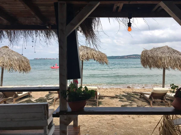 Plaj çubuğundan görüntülemek için deniz, ahşap yapı, şezlong şemsiye, şişme Flamingo, kumlu plajı ile