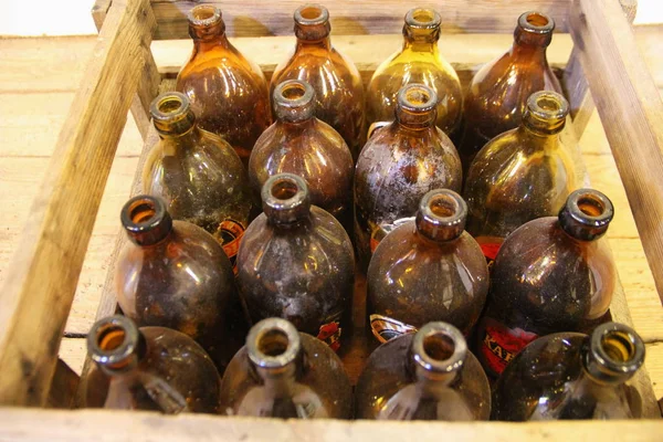 retro beer bottles in wooden box, thick brown glass, covered with time dust, stand neck up, vintage stuff