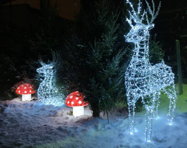 Noel kompozisyon takı, parlayan hasır geyik ve yavrusu, iğne yapraklı ağaçlar, yakın kar yere, sinek agarics, sıradışı bir kombinasyon