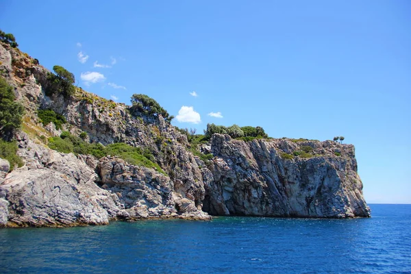 Güçlü bir kaya, küçük yeşil bir bitki örtüsü olan bir dağ mavi denize çıkıyor, güneşli, açık bir gün, Türkiye 'nin güzel doğası